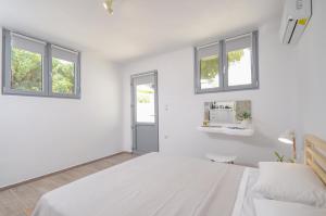 a white bedroom with a large bed and windows at Sea & Wind in Mikri Vigla