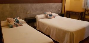 a hotel room with two beds with pillows on them at Hostal Fisterra in Lugo