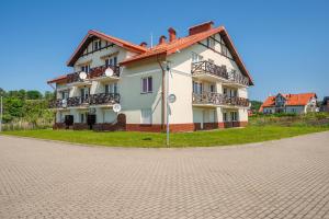 a large building on a grassy area with a road at Niska, Sun & Snow in Krynica Morska