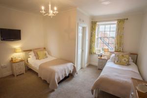 1 dormitorio con 2 camas y lámpara de araña en Market Cross Guest House en Belford