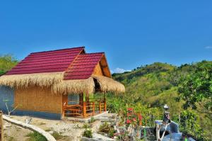 a small hut with a red roof on a hill at Aryaginata Cliff Cottages in Nusa Penida