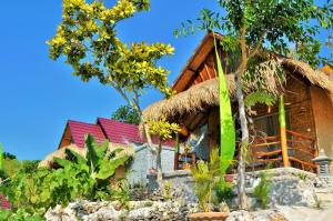 a house with a thatched roof and trees at Aryaginata Cliff Cottages in Nusa Penida