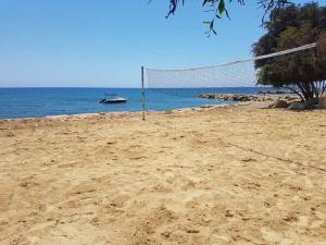 a volleyball net on a beach with a boat in the water at Elya Beach Luxury Suites in Ayios Theodhoros