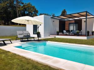 una piscina con sombrilla y una casa en Chalet Mia Sear Areas en Sanxenxo