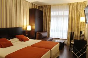 a hotel room with a bed and a chair at Hotel Conde Duque Bilbao in Bilbao