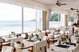 a restaurant with white tables and chairs and the ocean at Coral Strand Smart Choice in Beau Vallon