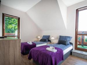 two beds in a room with purple sheets at Dom 8-osobowy z jacuzzi, balią, sauną - Agroturystyka u Moniki in Masłów