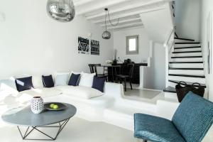 a white living room with a white couch and a table at Nimbus Mykonos in Agios Stefanos