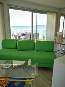 a living room with a green couch and a view of the ocean at Le Splendid in La Baule