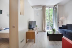 sala de estar con cama, TV y sofá en Tendency Apartments 7, en Barcelona