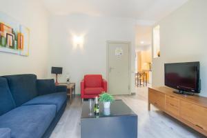 uma sala de estar com um sofá azul e uma televisão em Tendency Apartments 7 em Barcelona