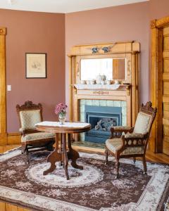 a living room with a table and chairs and a fireplace at Reynolds House Inn in Barre