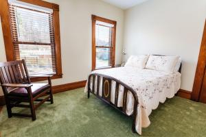 um quarto com uma cama, uma cadeira e 2 janelas em Reynolds House Inn em Barre