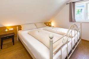 a white bed in a room with a window at Ferienhaus Bachschlössle in Lochau