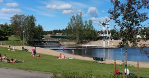 um grupo de pessoas sentadas na grama perto de um corpo de água em Grand Hotell Bollnäs em Bollnäs