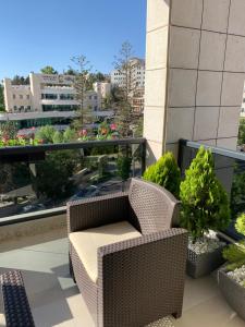 Ramallah Modern Apartment في رام الله: شرفة مع كرسي الخوص وبعض النباتات