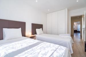 リスボンにあるAkicity Lisboa Pearl IIのベッドルーム1室(白いシーツが備わるベッド2台付)
