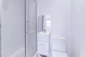 a white bathroom with a sink and a mirror at Quiet cosy rooms in Harrow