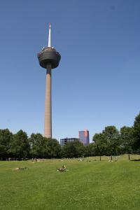 科隆的住宿－Weltempfänger Backpacker Hostel，公园里一座塔楼,人们躺在草地上
