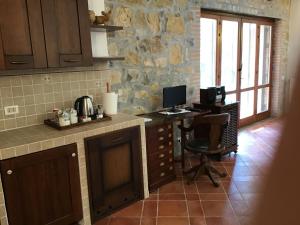 a kitchen with a desk with a computer and a chair at casa Anna De Croy in Magliano in Toscana
