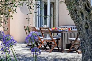 une table et des chaises sur une terrasse avec des fleurs violettes dans l'établissement STONE ROSE VILLA, à Ágios Ioánnis