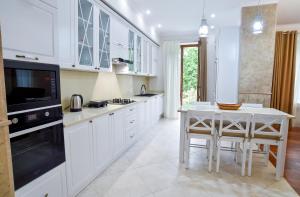 uma cozinha com armários brancos, uma mesa e um micro-ondas em Exclusive Apartament the Heart of Old Kutaisi em Kutaisi