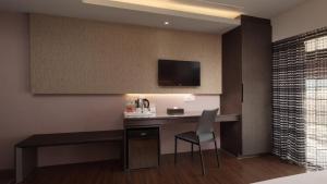 a hotel room with a desk with a television on the wall at Fine Hotel in Kaohsiung