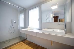 bagno bianco con lavandino e specchio di Maison Alliod a Saint Vincent