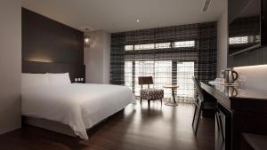 a bedroom with a white bed and a desk and a window at Fine Hotel in Kaohsiung