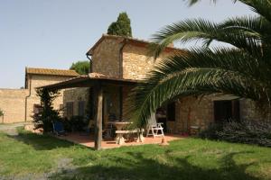 ein Haus mit einer Terrasse mit einem Tisch und einer Palme in der Unterkunft Agriturismo Il Poggio in Casale Marittimo