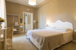 a bedroom with a white bed and a chair at BluLassù City Center Rooms in Cagliari