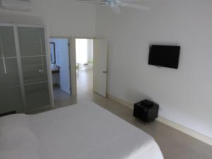 Schlafzimmer mit einem weißen Bett und einem Flachbild-TV in der Unterkunft Tamarindo in San Andrés