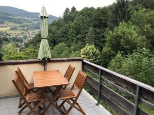 a table and two chairs and an umbrella on a balcony at Gîte du ROCHER in Lapoutroie