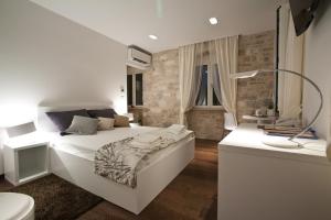 1 dormitorio con 1 cama blanca grande y baño en Speruna Luxury Inn, en Split