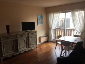 a living room with a television and a table with chairs at Coeur Deauville Grand 3 pièces avec Parking in Deauville