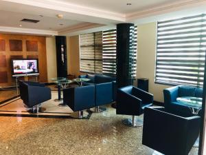 una sala de espera con sillas azules y TV en Golden Park Hotel en Luanda
