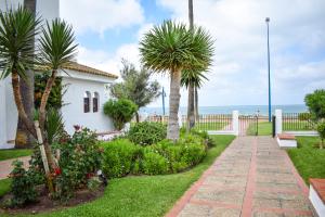 una pasarela frente a una casa con palmeras y el océano en Apartamento Barrosaplaya1, en Chiclana de la Frontera