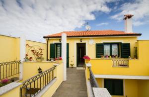 a yellow house with a porch and a balcony at Casa Veronica in SantʼAntìoco
