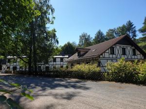 a white and black house with a fence and trees at Sternhaus-Harz in Gernrode - Harz