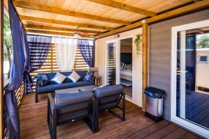 un portico con divano e sedie su una terrazza di Mobile Home HappyNest a Biograd na Moru