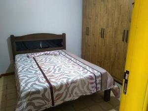 Cama pequeña en habitación con armario de madera en Castanheiras 3 Quartos, en Guarapari