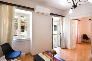 ein Wohnzimmer mit weißen Wänden und einem blauen Stuhl in der Unterkunft Andrew's Old Town Apartment by CorfuEscapes in Korfu-Stadt