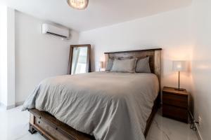 a white bedroom with a large bed and a mirror at Fantastic Mission Beach condo steps to the Beach in San Diego