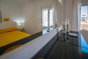 um quarto com uma cama amarela e uma mesa de vidro em Apartamento El Rayo Verde em Cádiz