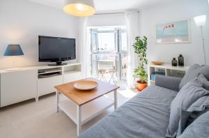 ein Wohnzimmer mit einem Sofa, einem TV und einem Tisch in der Unterkunft Apartamento El Rayo Verde in Cádiz