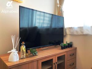 a large flat screen tv sitting on a wooden entertainment center at Alphabed Takamatsustation 301 / Vacation STAY 38150 in Takamatsu