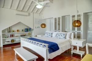 a white bedroom with a bed and a ceiling fan at Hotel Agua Azul Beach Resort in Barú