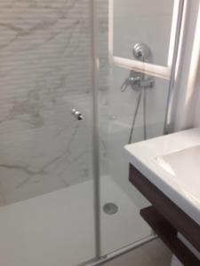 een badkamer met een glazen douche en een wastafel bij APARTAMENT W BEL MARE in Międzyzdroje