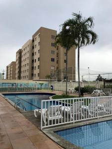 einen Pool mit einer Palme und einem Gebäude in der Unterkunft APTº NOVO NO SANTA LÚCIA in Aracaju