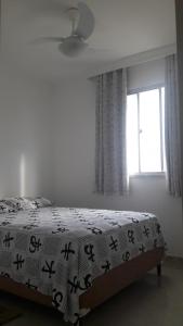 a bedroom with a bed with a blanket with writing on it at Apart Varanda do Poxim in Aracaju